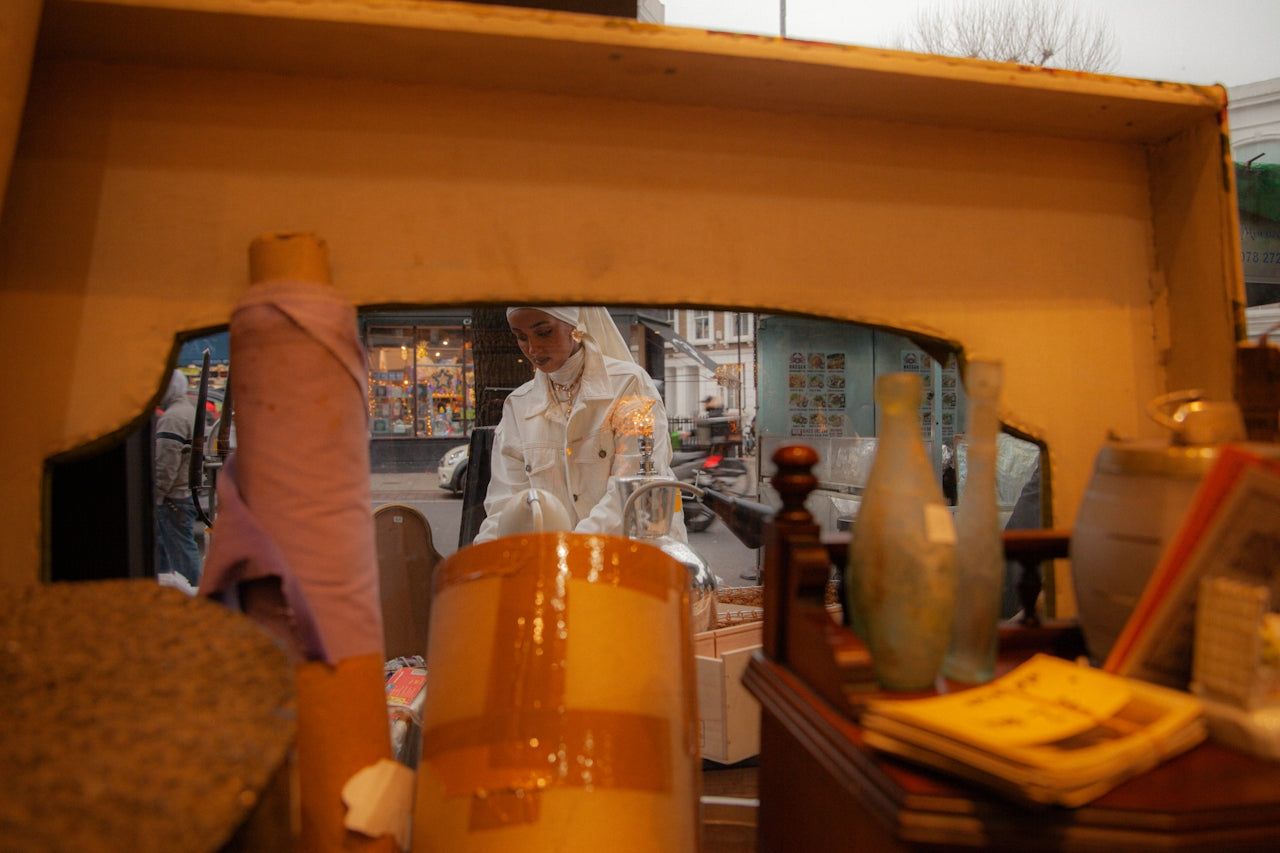 an artist in white reflected in a warm golden vintage mirror, looking down at her work