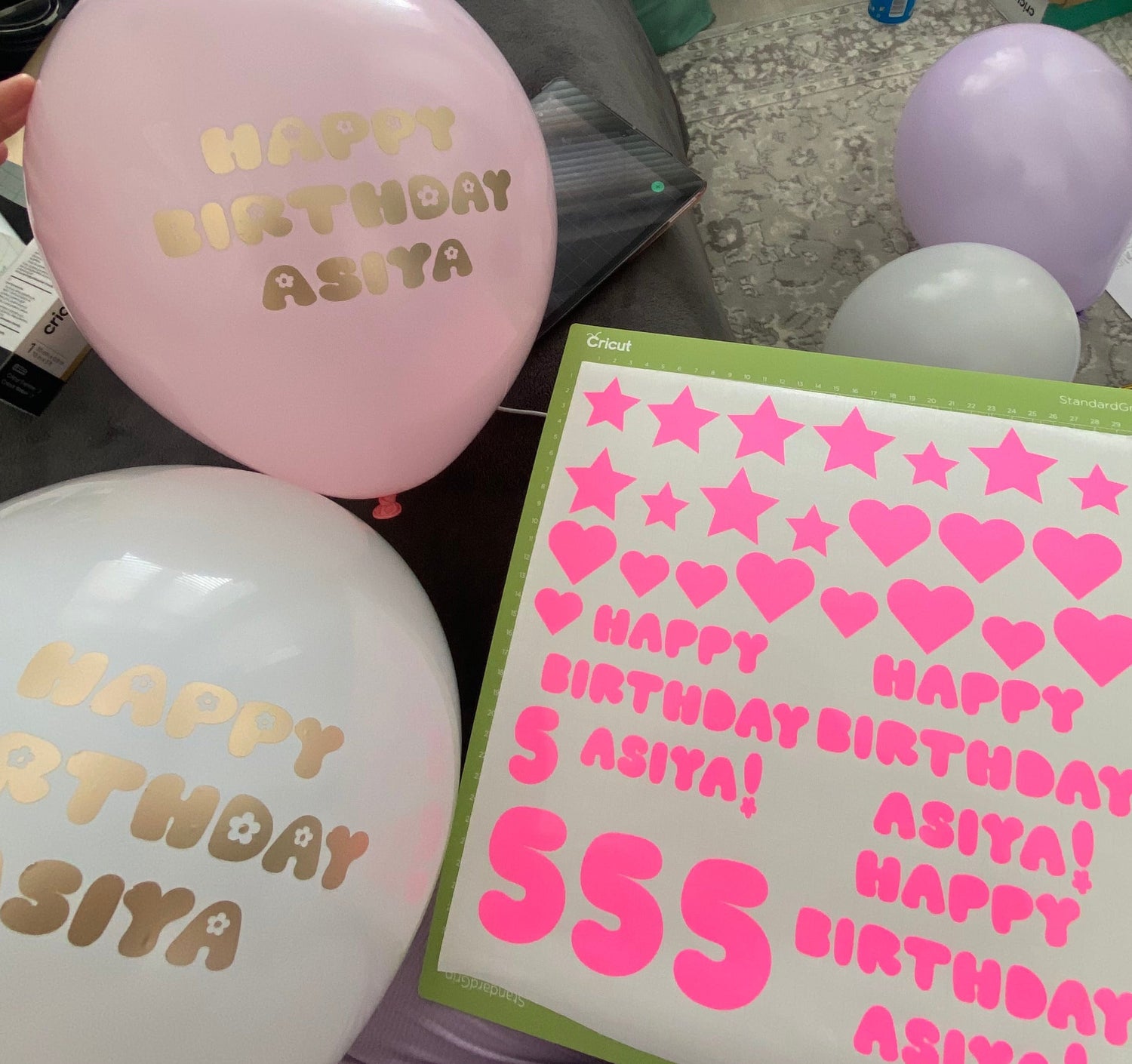 Pink and white balloons with 'Happy Birthday Asiya' text, and a sheet of pink heart and star stickers.